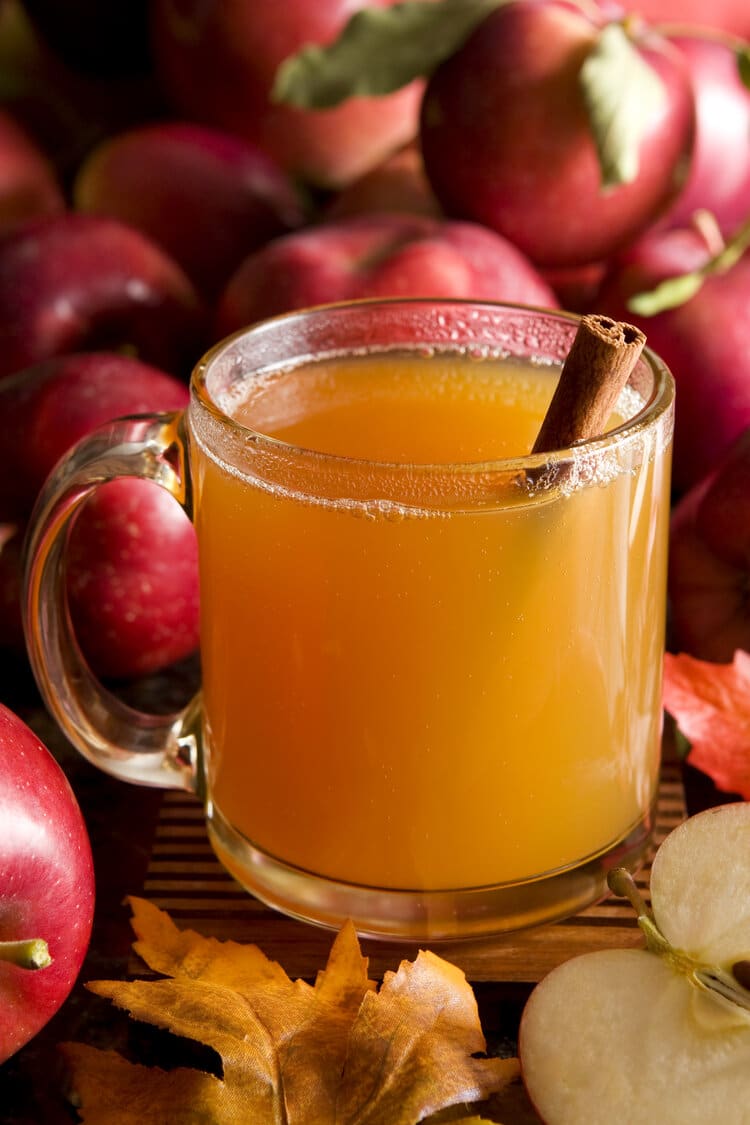 Apple Cider In Glass Mug With Cinnamon Stick Next To Apples